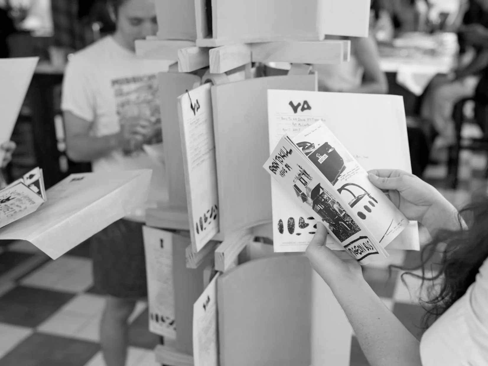 A visitor looking through printed works on the Zine Assembly display