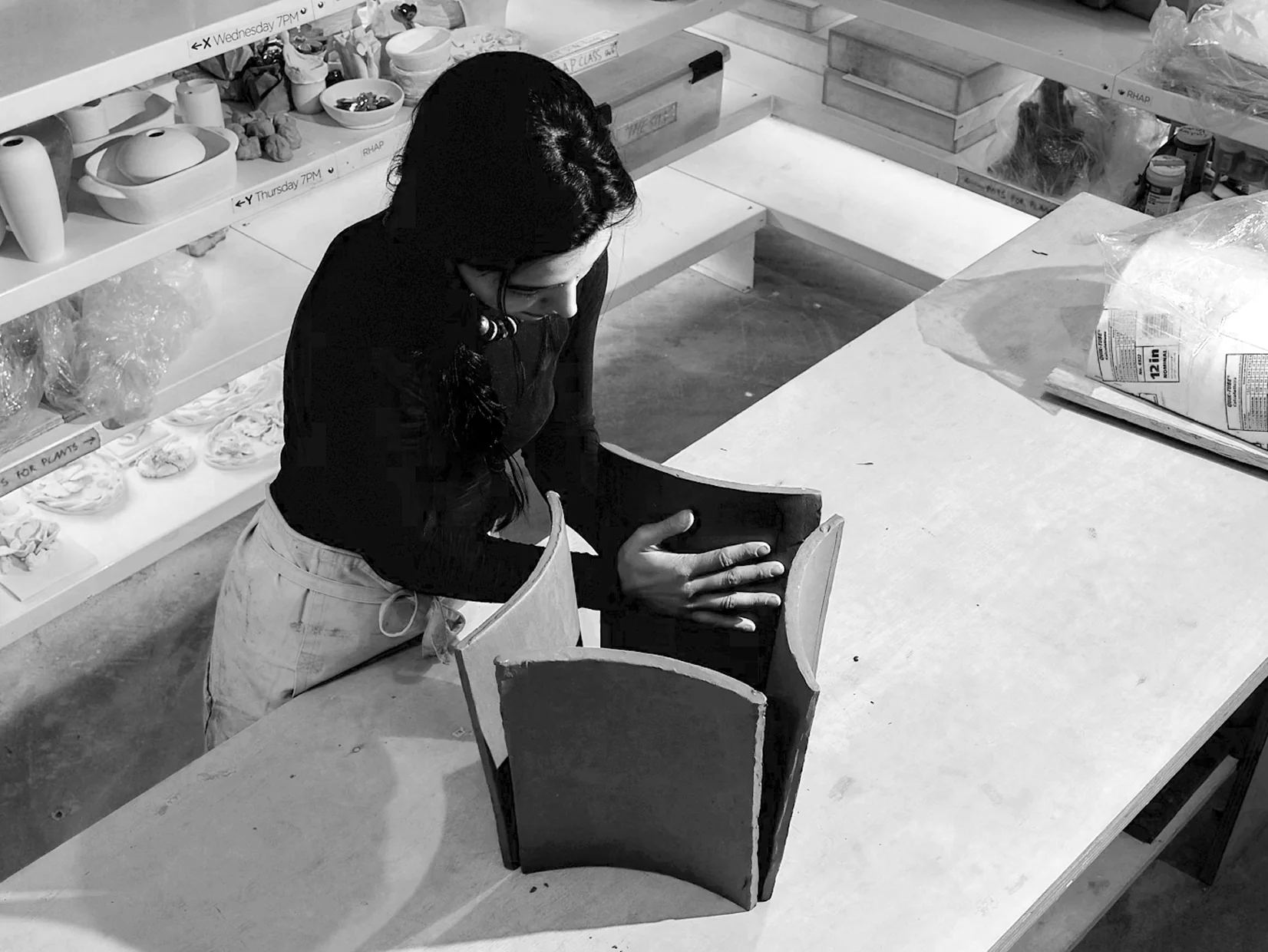 A person assembling a ceramic display structure at a worktable